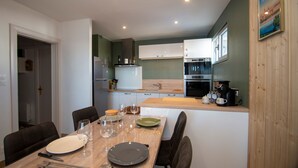 Una cocina moderna con armarios blancos, una encimera de madera y una zona de comedor con una mesa dispuesta para dos.