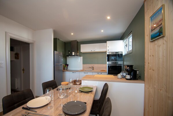 A modern kitchen with white cabinets, a wooden countertop, and a dining area with a table set for two.