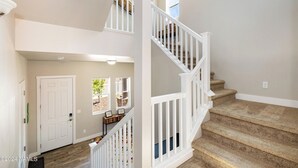 Un intérieur de maison à plusieurs niveaux, comprenant un escalier, une porte et une fenêtre donnant sur l’extérieur.