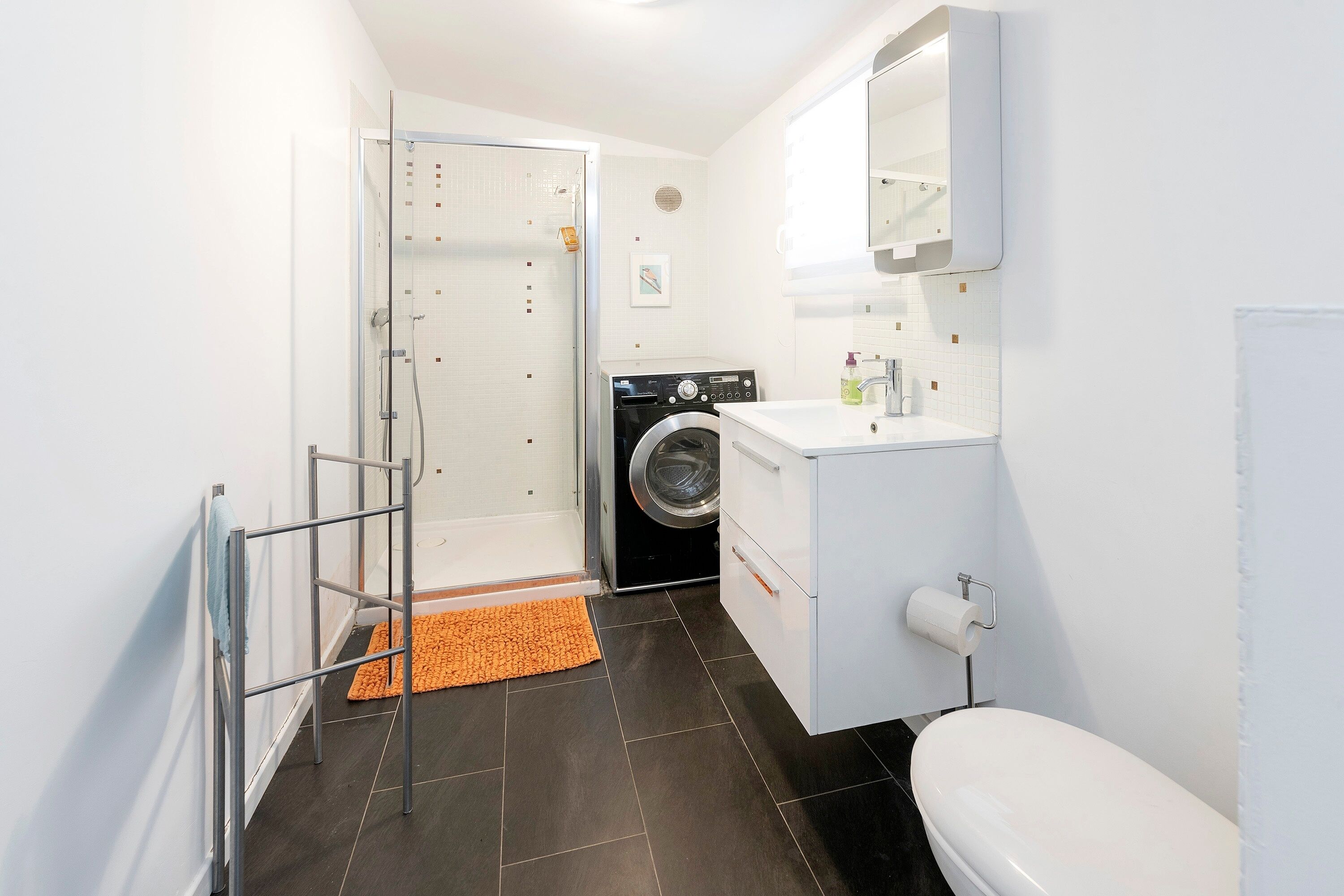 Een kleine badkamer met een douche, een wasmachine en een toilet.
