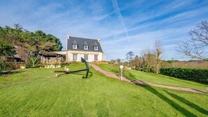 A large house with a well-maintained lawn, a gazebo, and a pathway leading to the entrance.