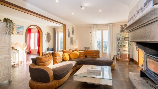 A modern living room with a sectional sofa, a glass coffee table, and a fireplace.