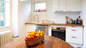 Una cucina moderna con mobili bianchi, un piano di lavoro in legno e un cesto di frutta sul tavolo.
