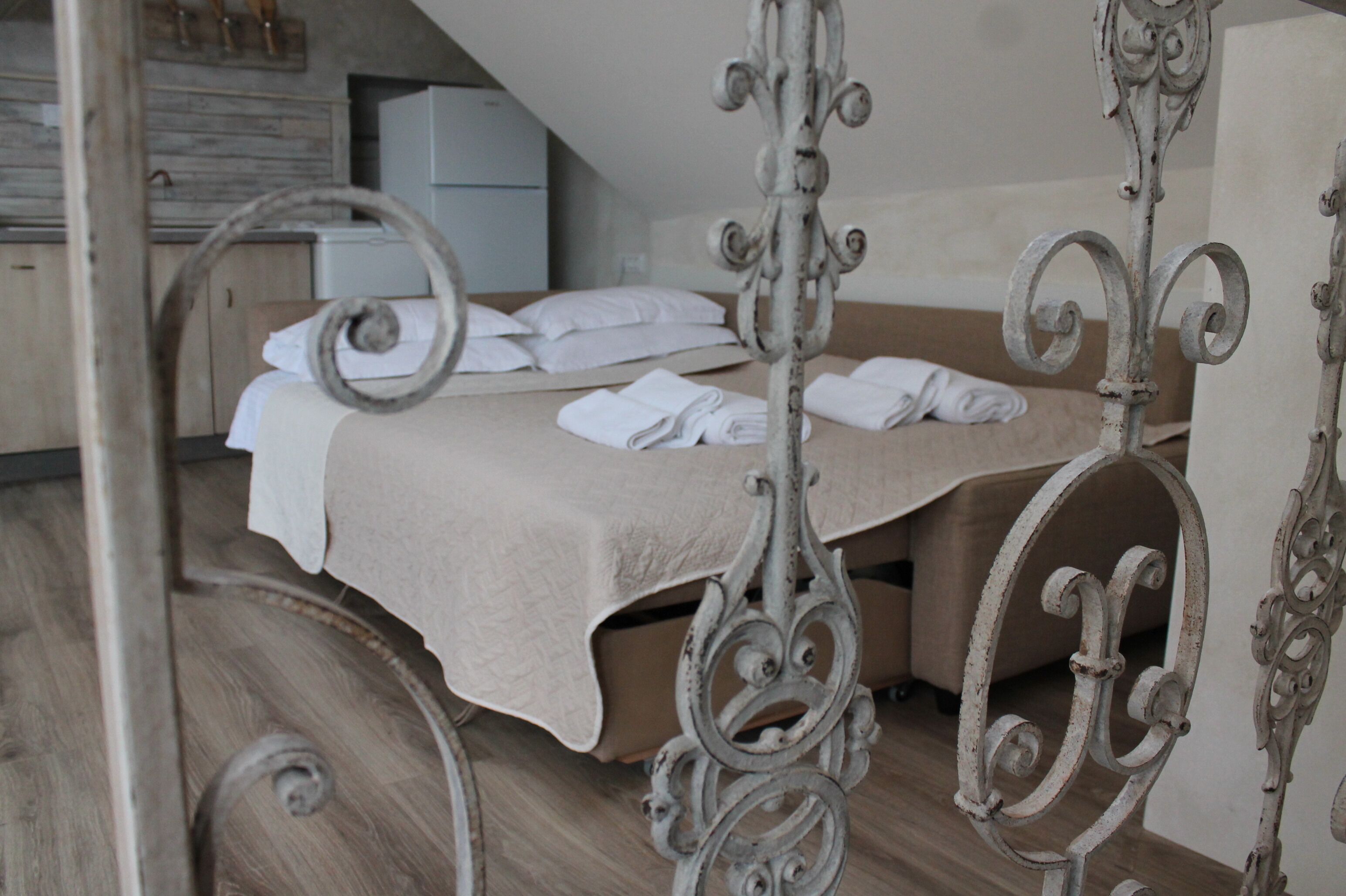 Een slaapkamer met een bed, een houten vloer en een witte muur.