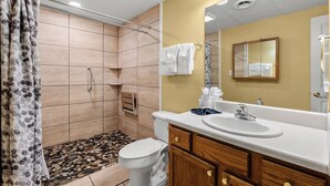 Ein Badezimmer mit Dusche, Toilette, Waschbecken und Holzschränken.
