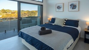 A modern bedroom with a large bed, a balcony, and two framed artworks on the wall. - Cove Landing Ocean View Apt-1,2&3 Sleeps 12 (Penneshaw)