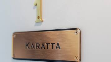Eine Namensplakette aus Messing mit dem Wort 'Karatta' an einer Wand befestigt.