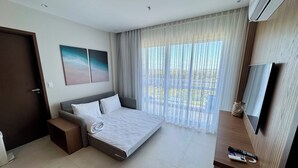 A modern hotel room with a large bed, a TV, and a view of the outdoors through sheer curtains. - Aqualand Resort (Salinópolis)