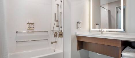 A modern bathroom with a bathtub, a vanity with a mirror, and toiletries.