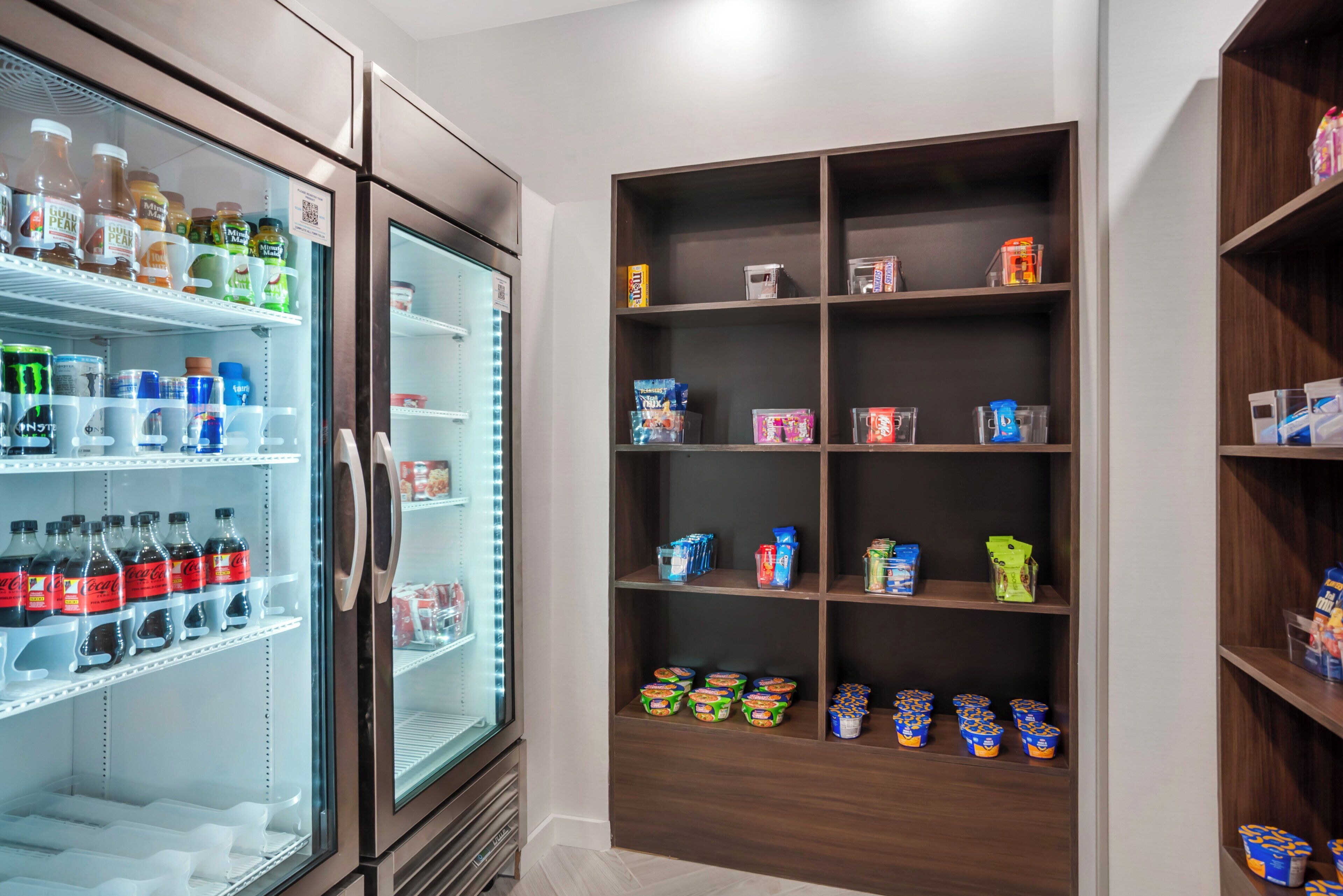 A refrigerated display with various beverages and a shelf stocked with packaged goods.