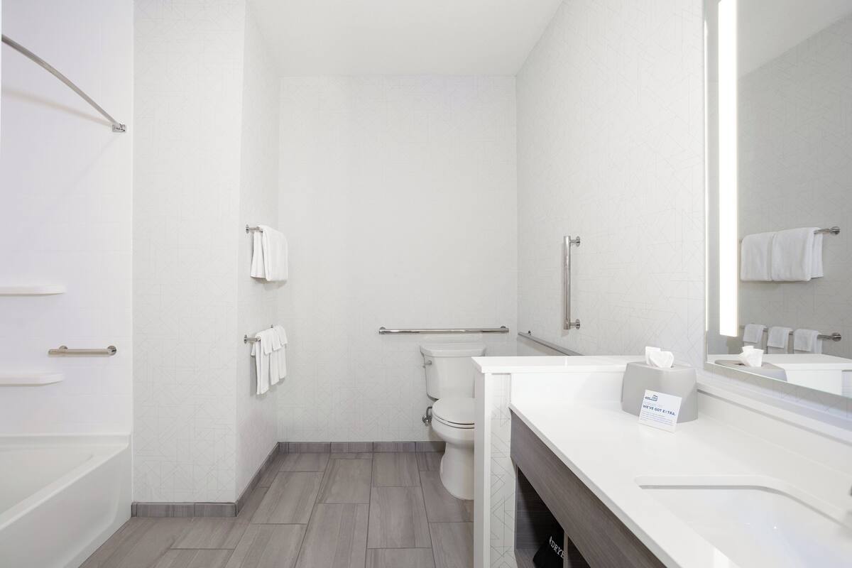 Une salle de bain moderne équipée de toilettes, d’une douche, d’un lavabo et d’un miroir.