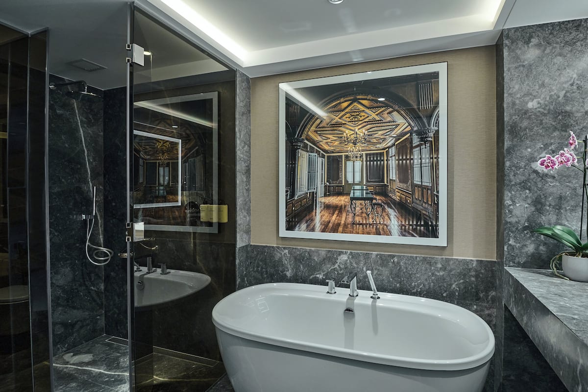 Un bagno moderno con una vasca freestanding, uno specchio grande e un quadro incorniciato di un interno sontuoso.