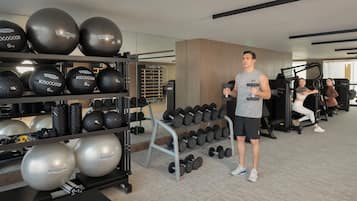 Ein Fitnessraum mit Trainingsgeräten, darunter Hanteln und Medizinbällen.