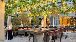 An outdoor bar area with stone tables and chairs, surrounded by greenery and string lights. - InterContinental Real Lima Miraflores by IHG (Lima)