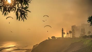 A coastal landscape with a lighthouse, buildings, and a road leading to the beach.