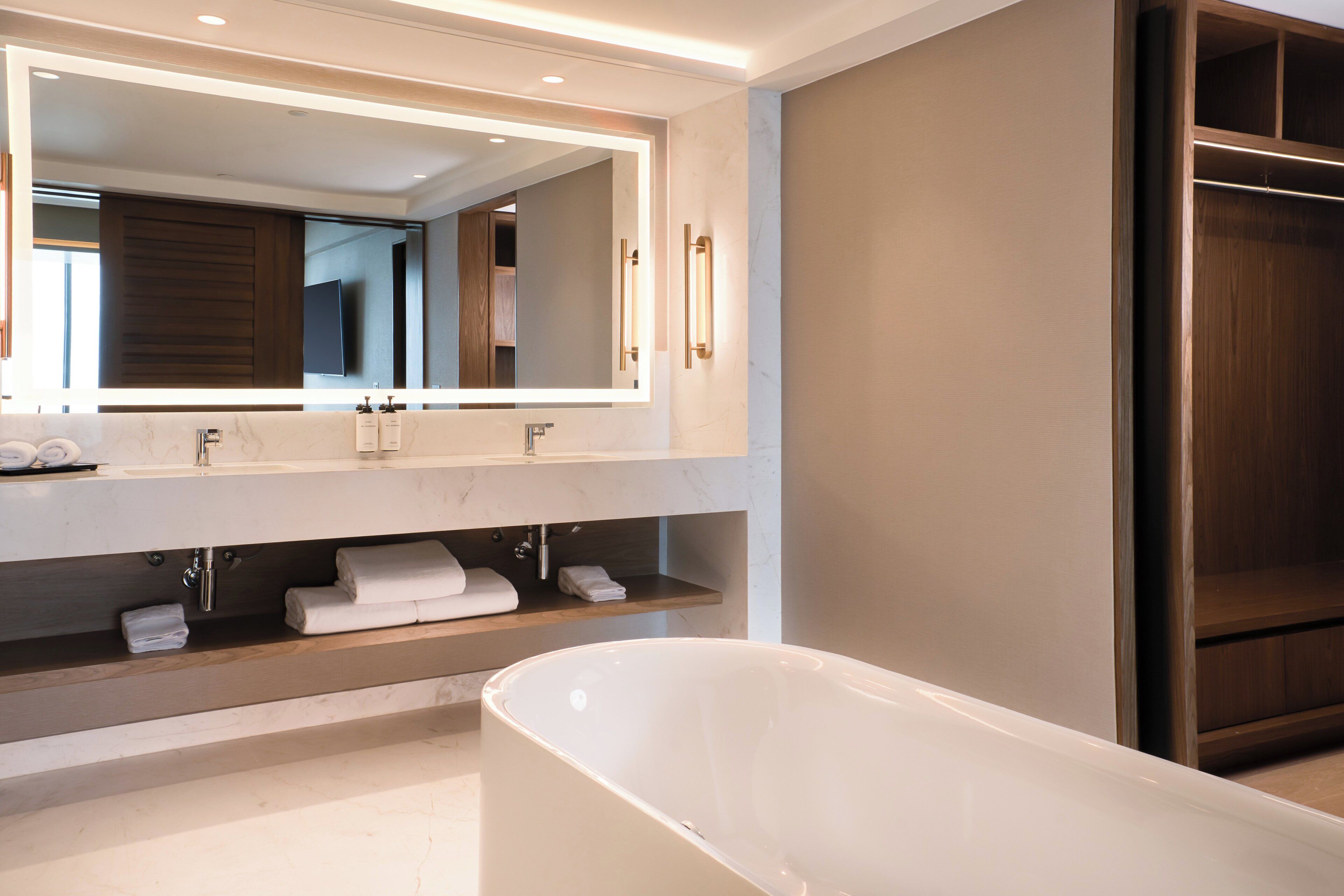 Un baño moderno con un espejo grande, una bañera y estantes de madera.