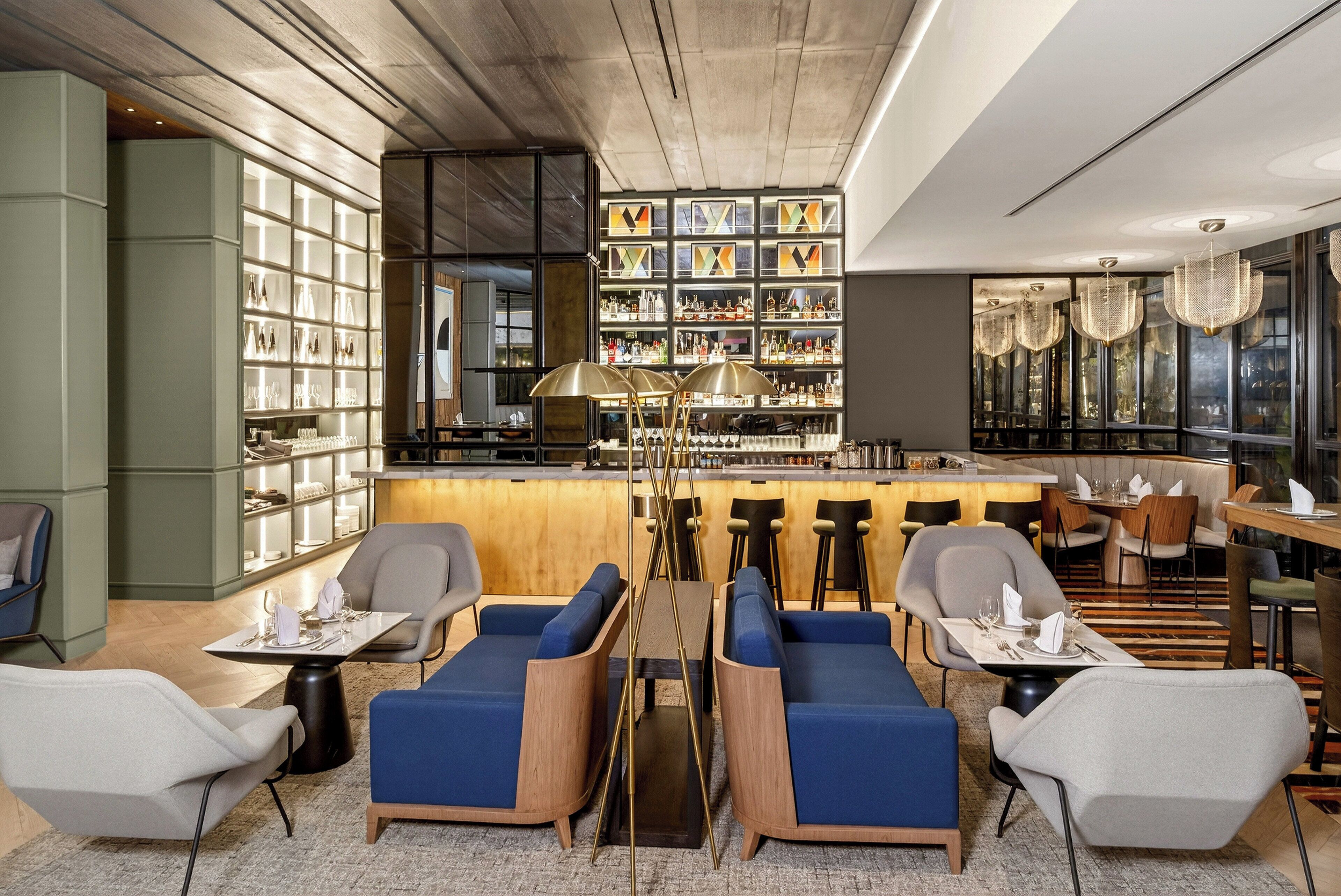 Un área de bar moderna con asientos, una barra y estanterías llenas de botellas.