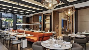 Un restaurante moderno con diversas opciones de asientos, incluyendo mesas redondas y una mesa larga comunitaria.