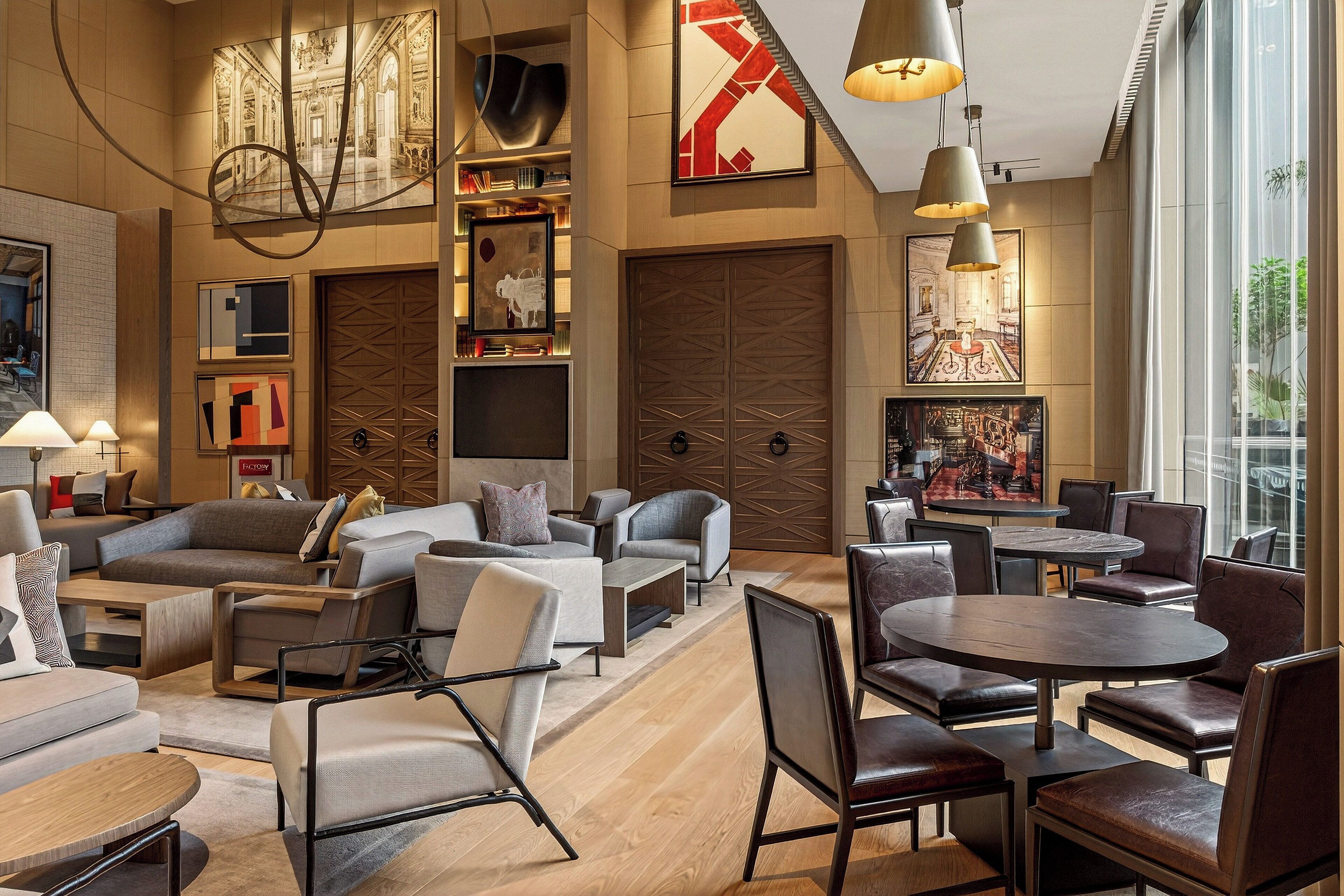 Ein stilvoller Lounge-Bereich mit Sofas, Sesseln und einem runden Tisch, der Kunstwerke und Bücherregale zeigt.