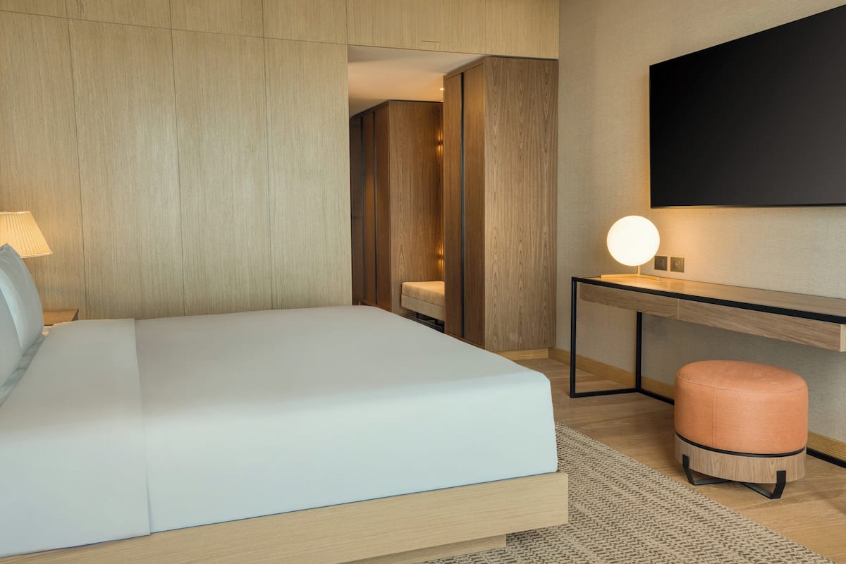 Una camera d'albergo moderna con un letto grande, una scrivania e un angolo salotto.