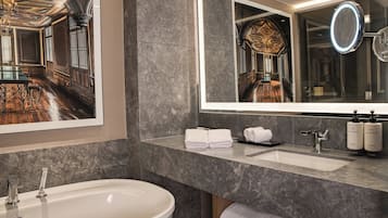 Un baño moderno con un espejo grande, una bañera y un tocador con artículos de aseo.