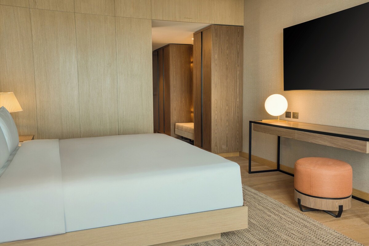 A modern hotel room with a large bed, a desk, and a seating area.
