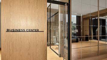 Un moderno centro de negocios con un pilar de madera identificado con la etiqueta “BUSINESS CENTER” y un separador de vidrio.