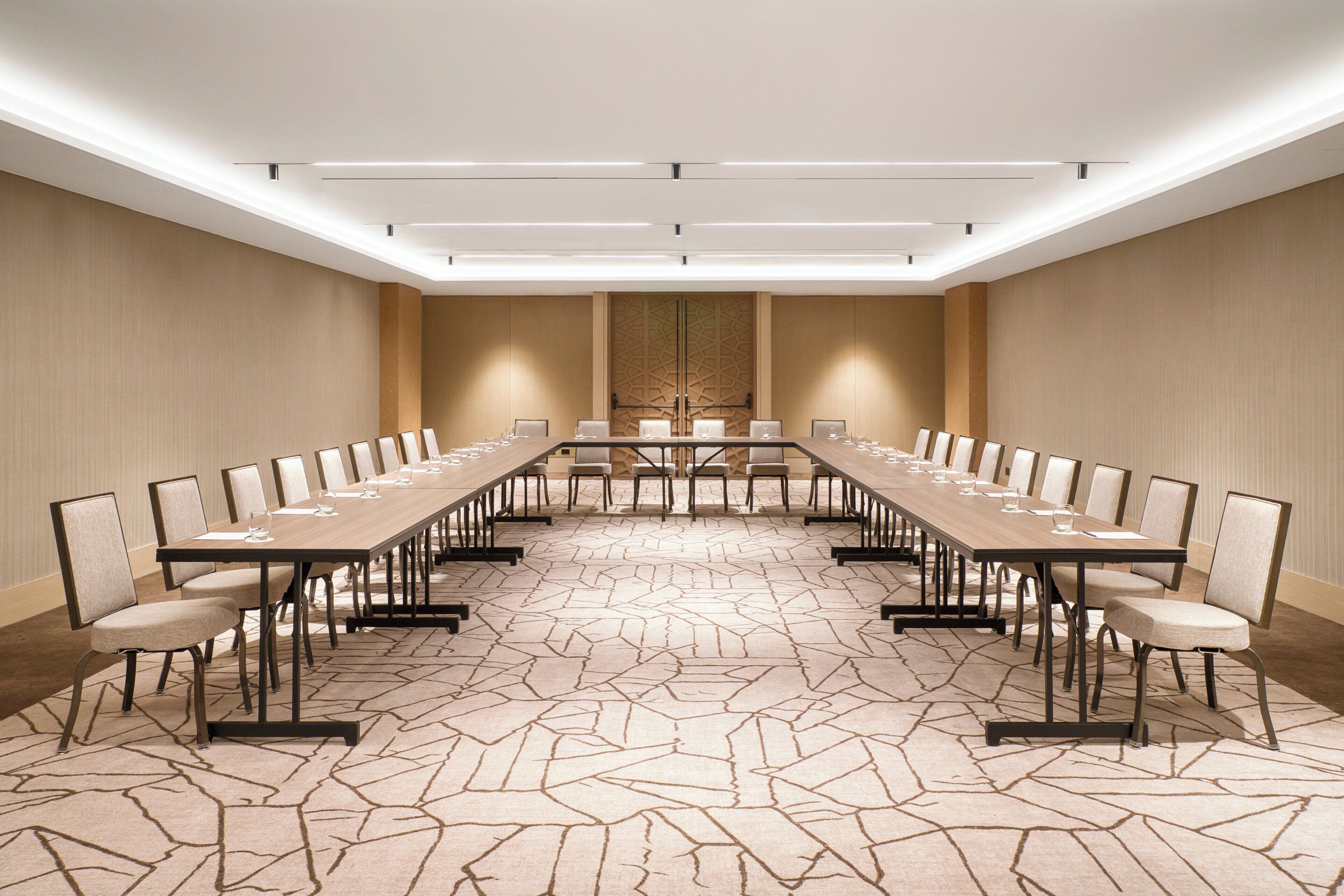 A conference room with a long table, chairs, and a patterned carpet.