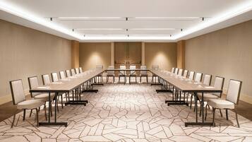 A conference room with a long table, chairs, and a patterned carpet.