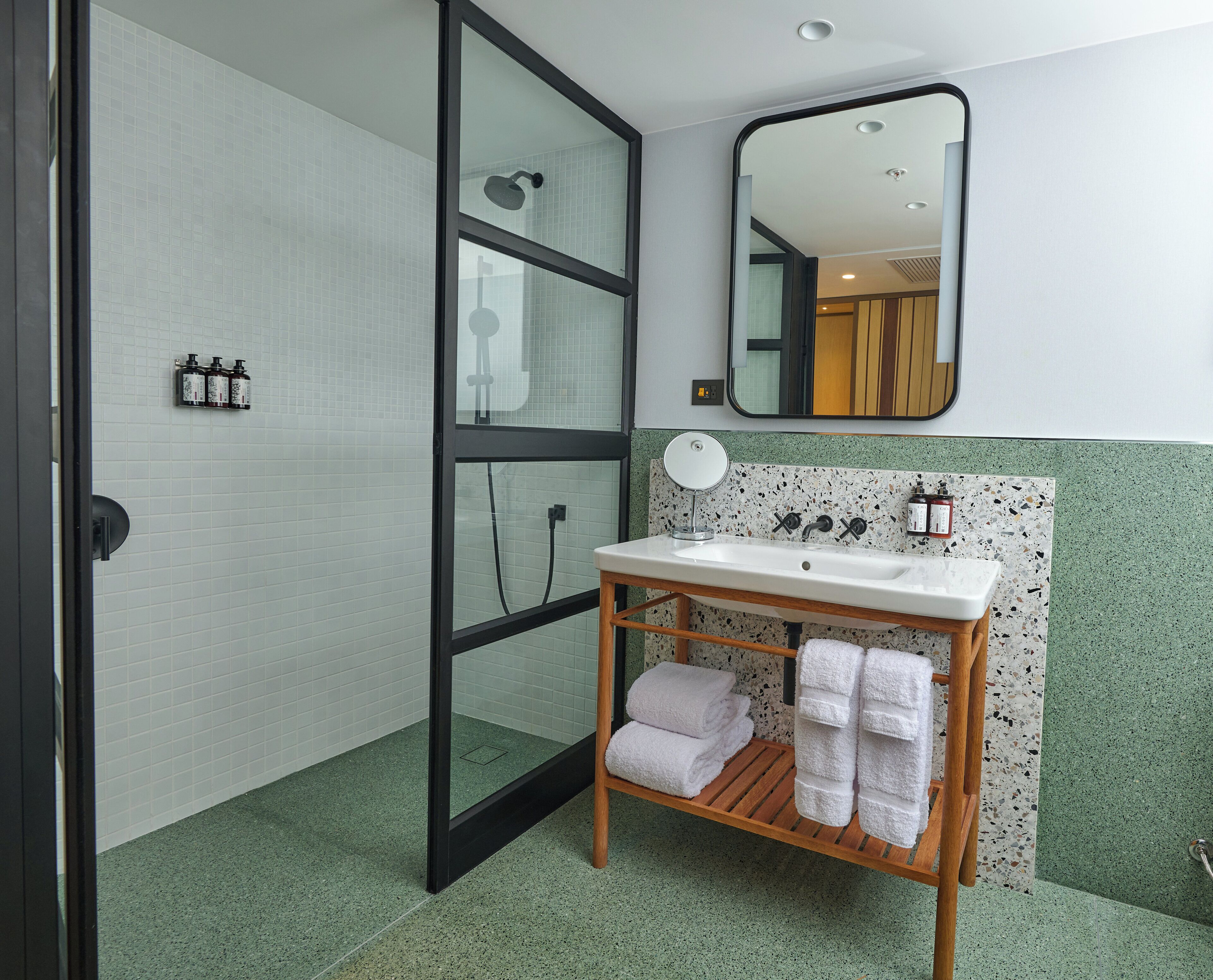 A bathroom with a white sink, wooden towel rack, and a mirror.