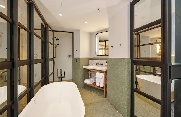 Un baño con bañera independiente, tocador con espejo y zona de ducha.
