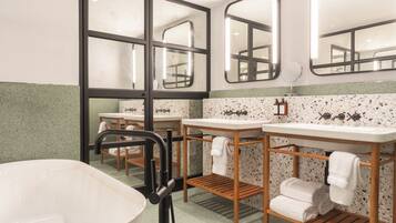 Un baño con dos lavamanos, una bañera y estantes de madera con toallas.