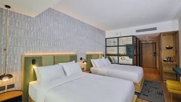 A hotel room with two beds, a desk, a chair, a small table, and a wardrobe.