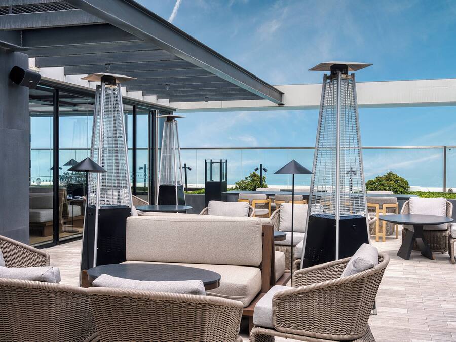 An outdoor seating area with wicker furniture, a glass enclosure, and a view of a tall building.