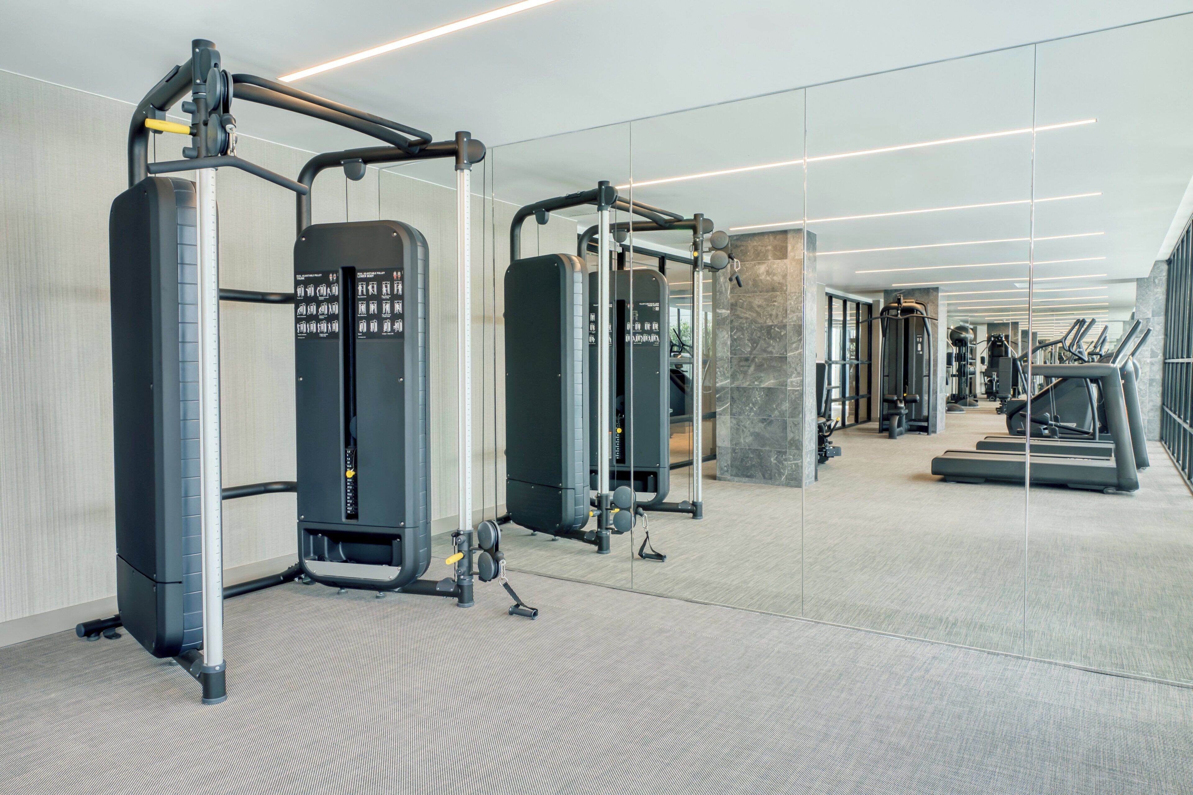 A modern gym with various exercise equipment, a mirrored wall, and a stone accent wall.