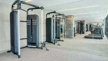 A modern gym with various exercise equipment, a mirrored wall, and a stone accent wall.