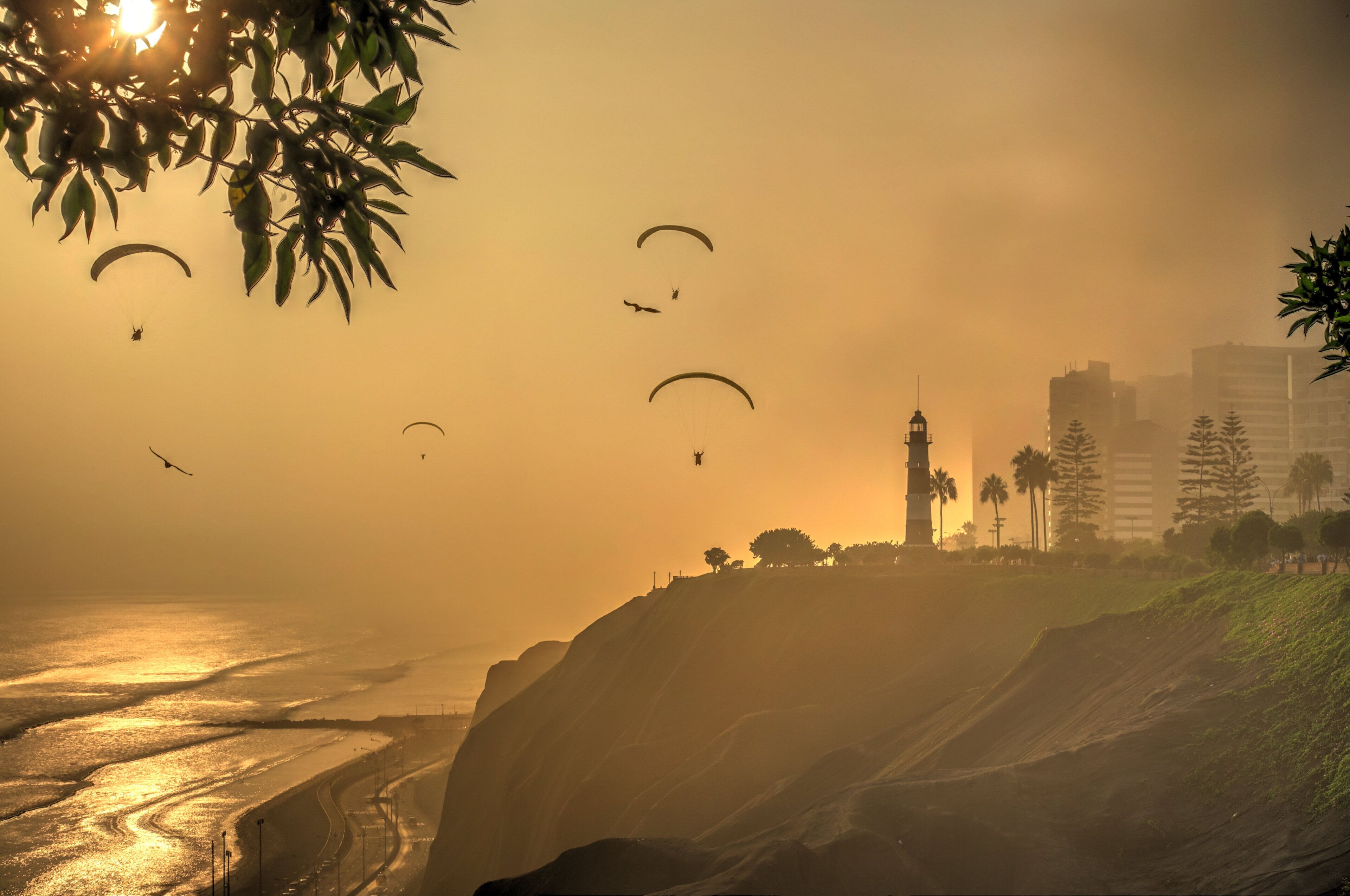 A coastal scene with a lighthouse, buildings, and a road leading to the beach.