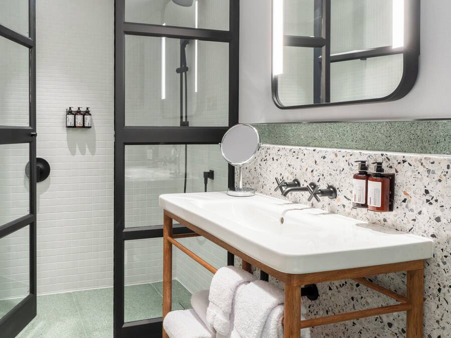 A bathroom with a white sink, wooden vanity, and a glass shower enclosure.