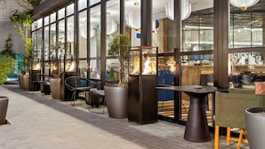 An outdoor seating area with modern furniture, large windows, and decorative lighting. - Hotel Indigo Lima Miraflores by IHG (Lima)