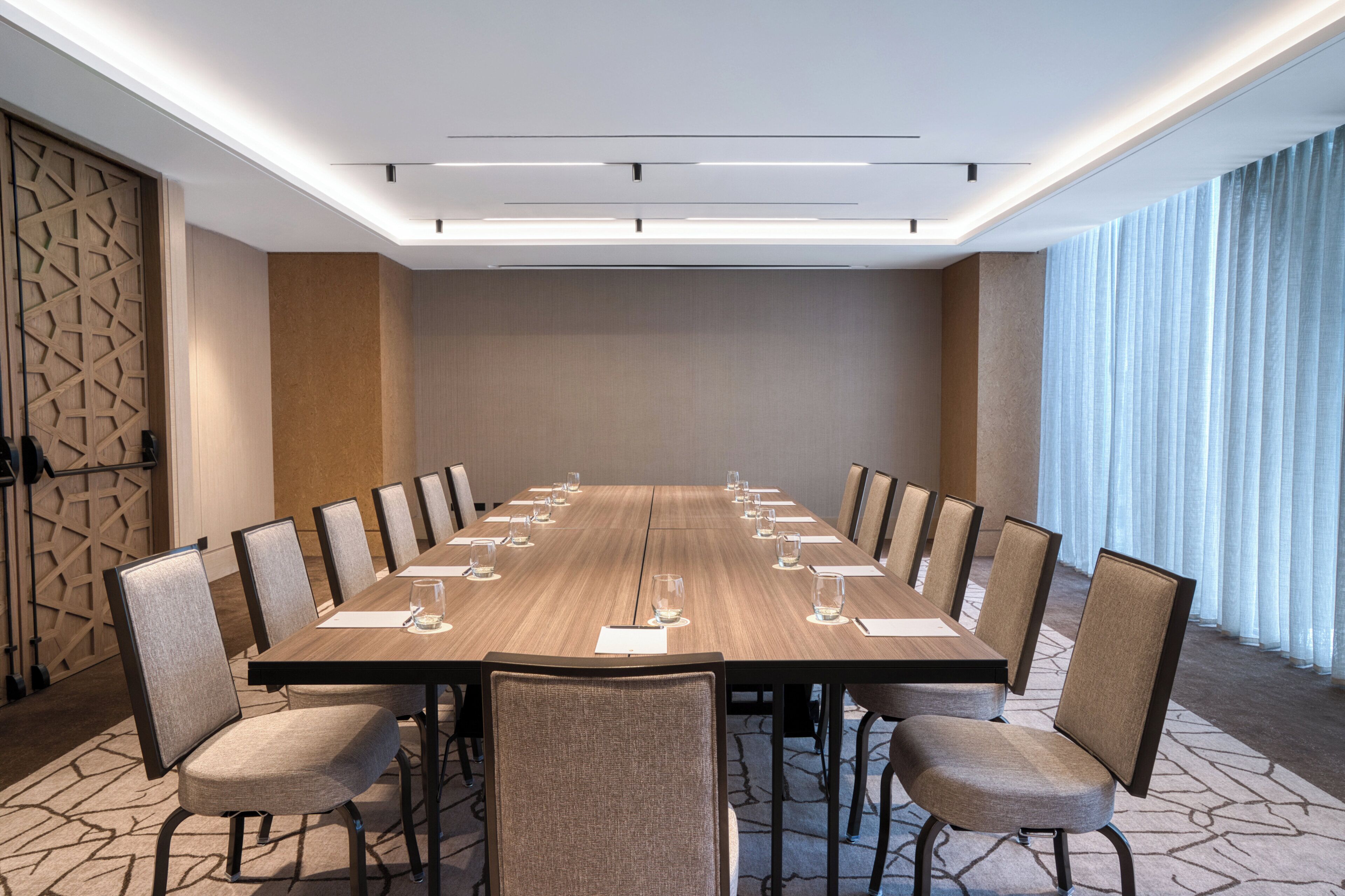 A conference room with a long table, chairs, and a modern ceiling design.