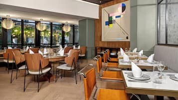 Un restaurante con suelo de madera, sillas modernas y mesas dispuestas para comer.