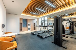 Une salle de sport moderne équipée de tapis de course, d’appareils de musculation et d’un mur entièrement recouvert de miroirs.
