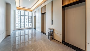 Een ruime, moderne lobby met een gepolijste marmeren vloer, grote ramen met uitzicht op de stad en een minimalistisch ontwerp met houten details.