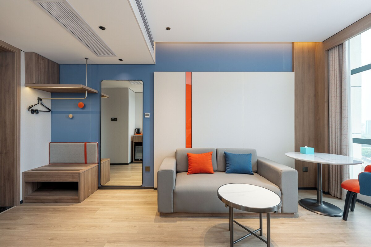 Une chambre d’hôtel moderne, équipée d’un canapé, d’une petite table et d’un luminaire suspendu.