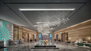 A spacious lobby with a central water feature, a reception desk, and modern seating areas. - Holiday Inn Wuhan Tianhe Airport by IHG (Wuhan)