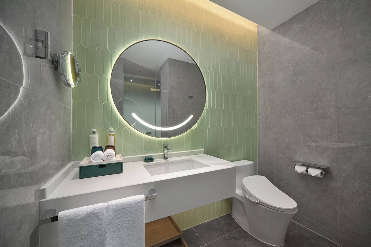 Un baño moderno con un espejo grande, un lavabo y un inodoro.