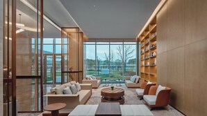 Ein modernes Interieur mit einer Sitzecke, großen Fenstern und einem Bücherregal.