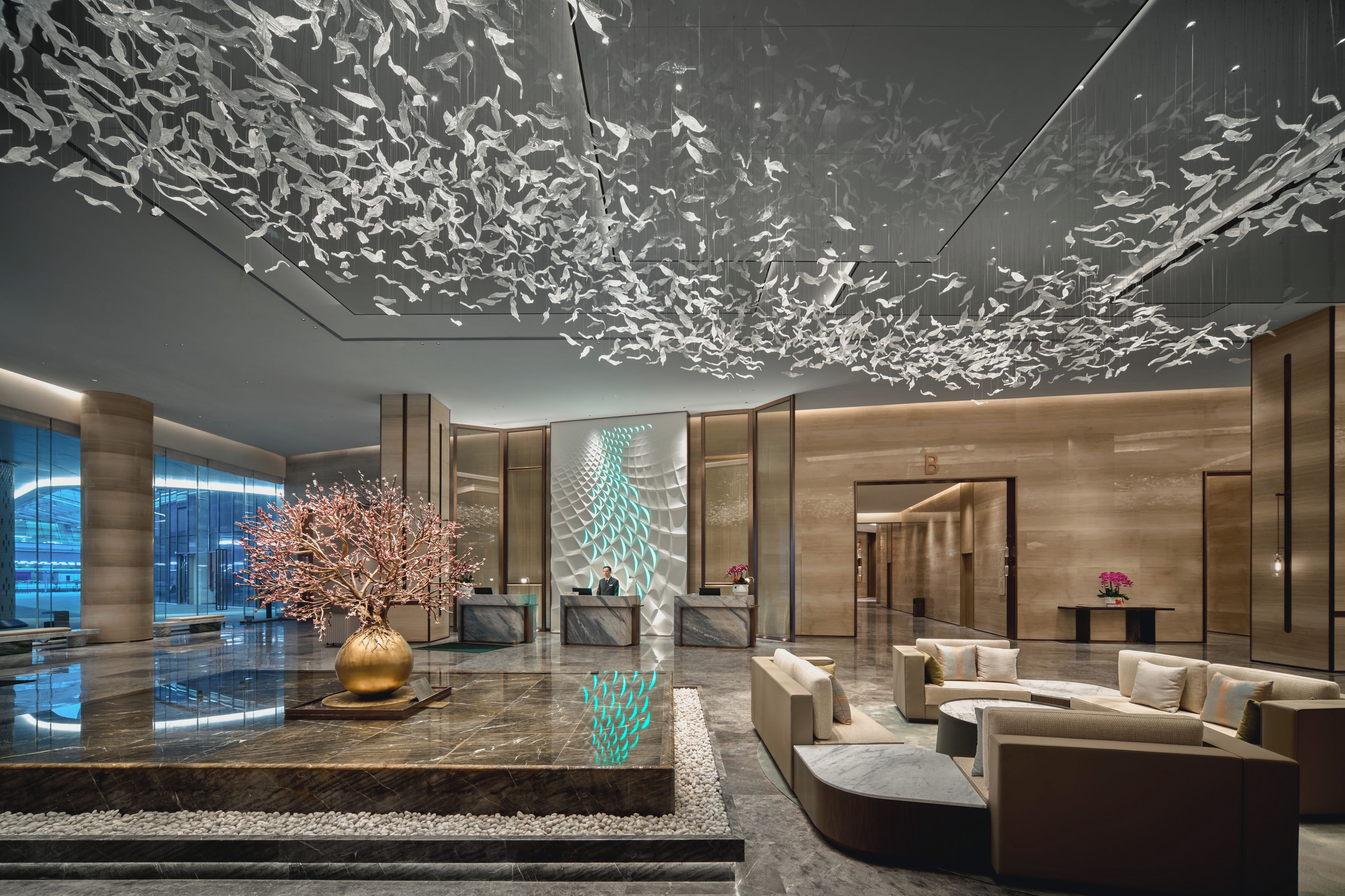 A modern lobby with a reception desk, seating area, and a decorative ceiling feature.