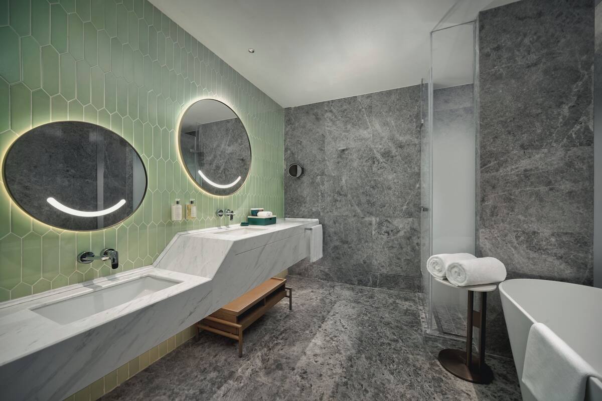 Un baño moderno con un espejo grande, dos lavamanos y una zona de ducha.