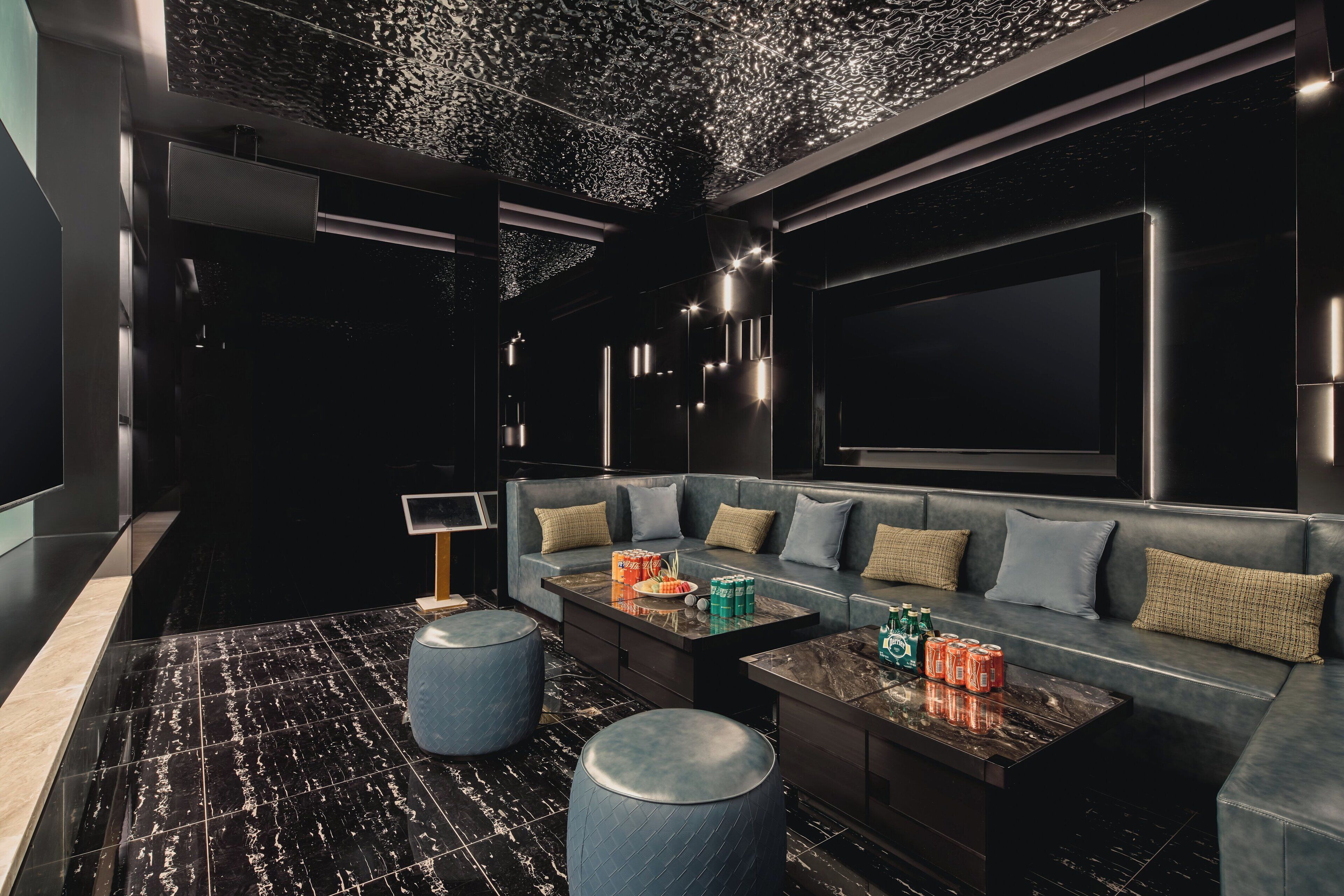 Egy modern, sötét színvilágú pihenősarok, amelyben egy kanapé, egy dohányzóasztal és egy textúrázott mintázatú mennyezet található.